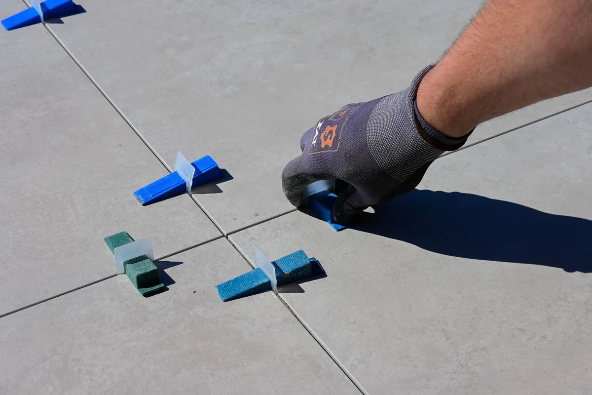 Large-format porcelain tile being leveled during installation